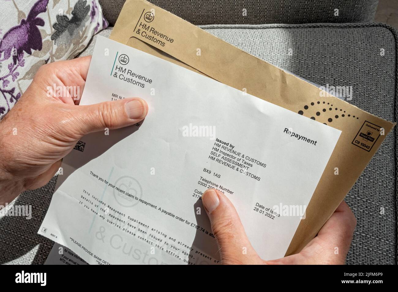 Close up of man person holding reading HMRC HM Revenue and Customs letter tax repayment payment England UK United Kingdom GB Great Britain Stock Photo