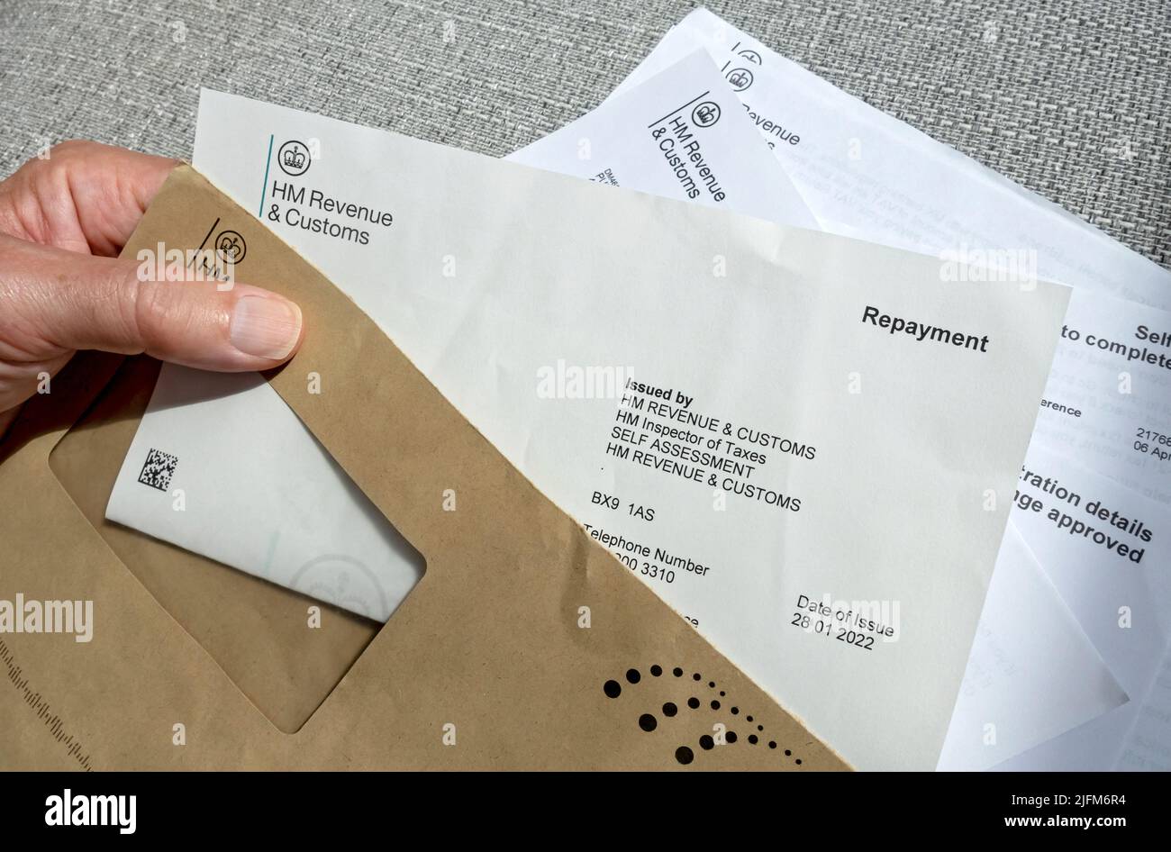 Close up of man person holding reading HMRC HM Revenue and Customs letter tax repayment payment England UK United Kingdom GB Great Britain Stock Photo