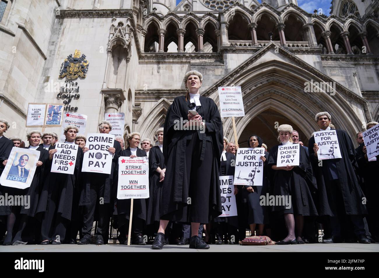 A junior barrister speaks to other criminal defence barristers as they gather outside the Royal Courts of Justice in London to support the ongoing Criminal Bar Association (CBA) action over Government set fees for legal aid advocacy work. Picture date: Monday July 4, 2022. Stock Photo