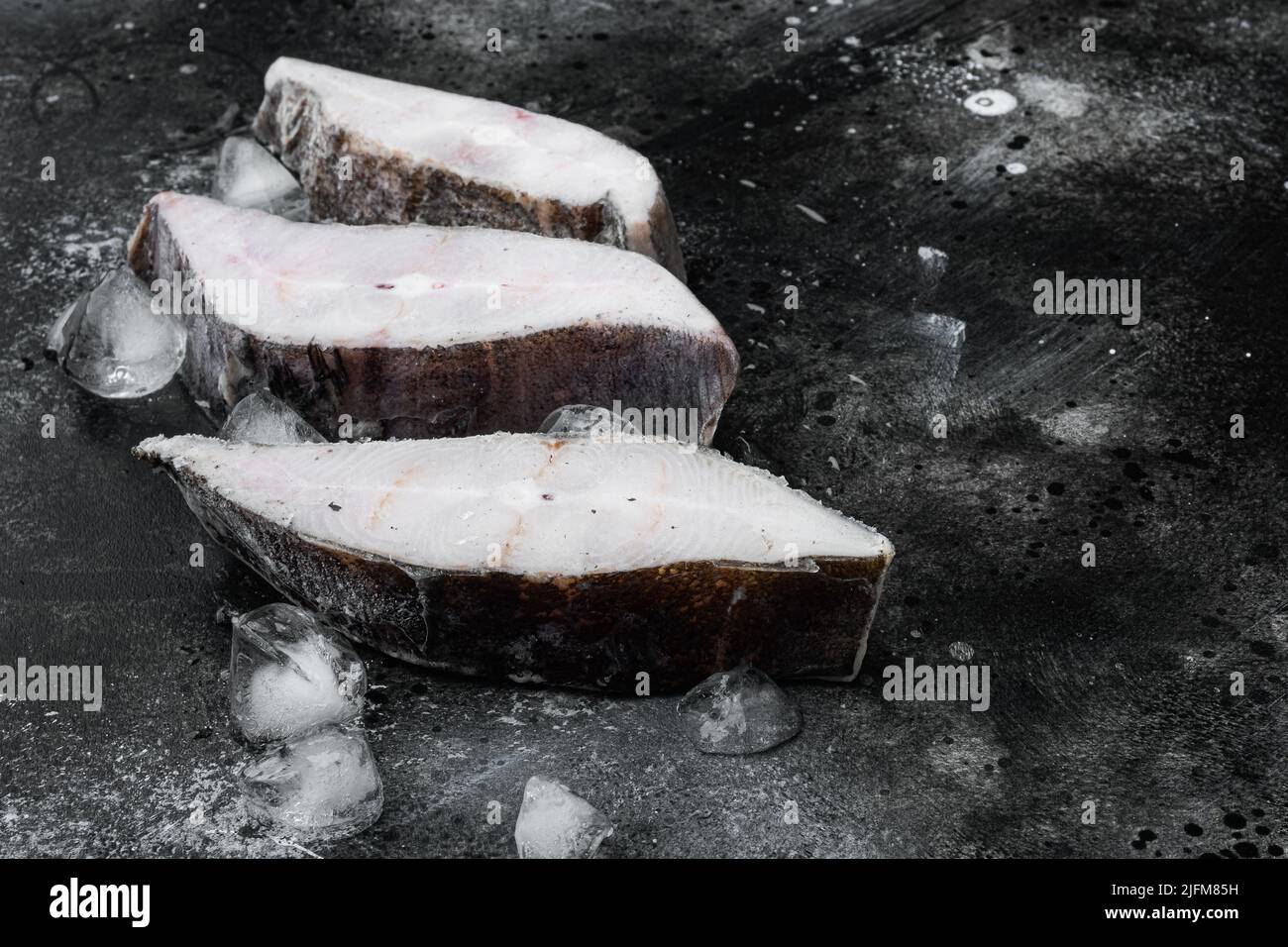 Halibut fish frozen steak, on black dark stone table background Stock ...