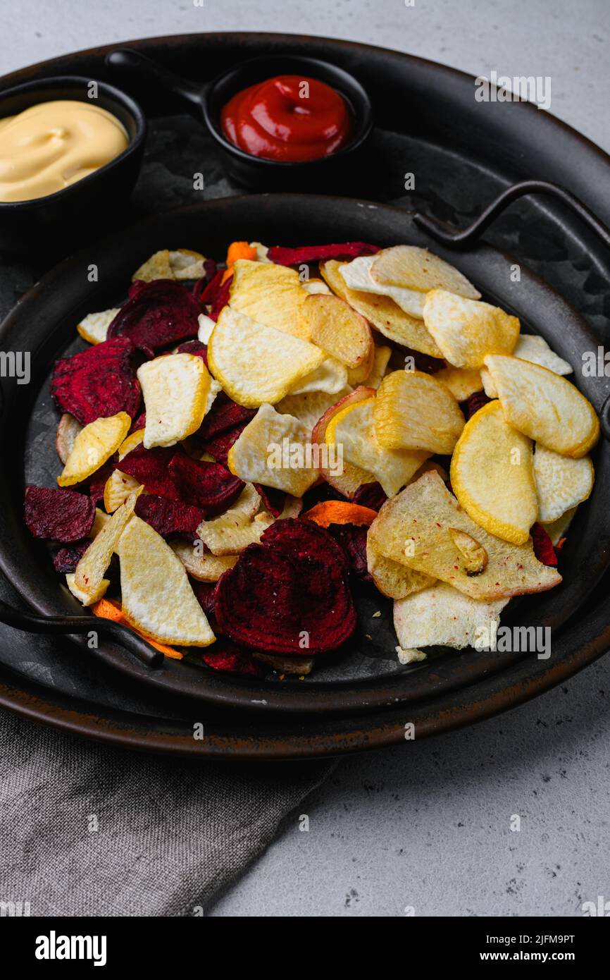 Dried vegetables chips, on gray stone table background Stock Photo