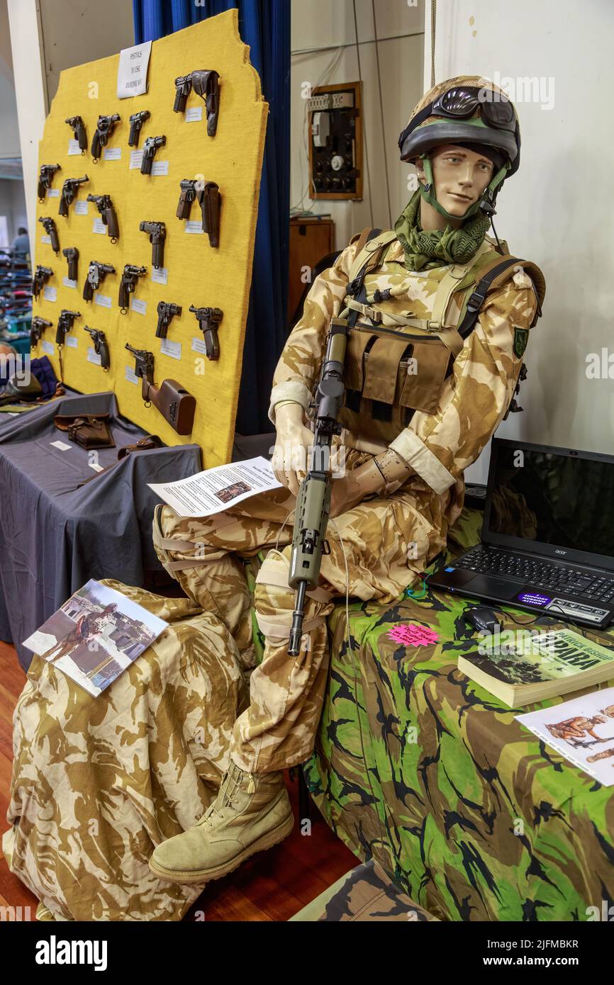 A mannequin dressed as a British paratrooper sits next to a collection of WWI pistols at a gun show. Tauranga, New Zealand Stock Photo