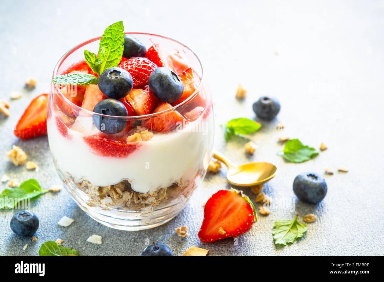 Parfait with cream or yogurt, jam and fresh strawberries in the glass