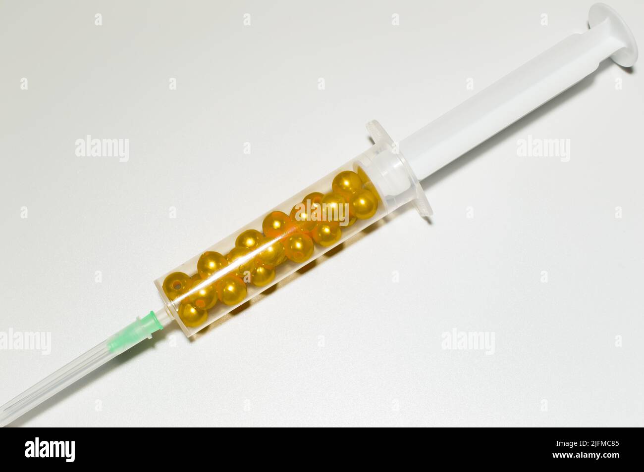 Medical syringes filled with golden beads on a white background