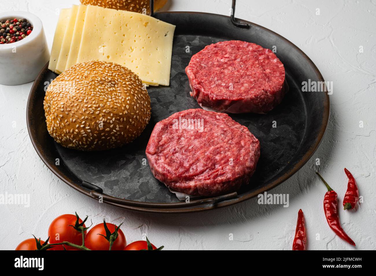 Raw fresh large beef burger on white stone table background Stock Photo