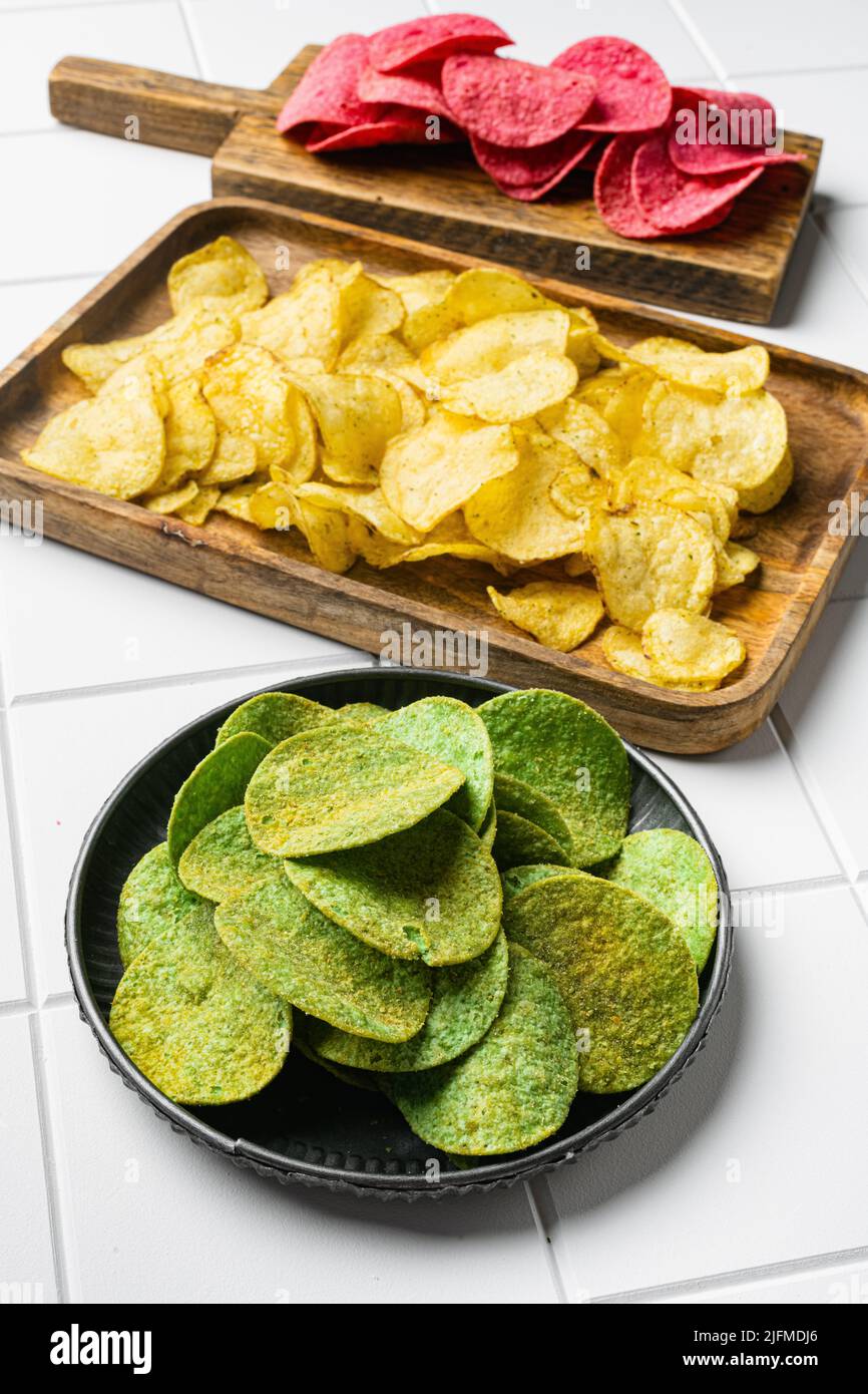 Green potato chips on white ceramic squared tile table background Stock