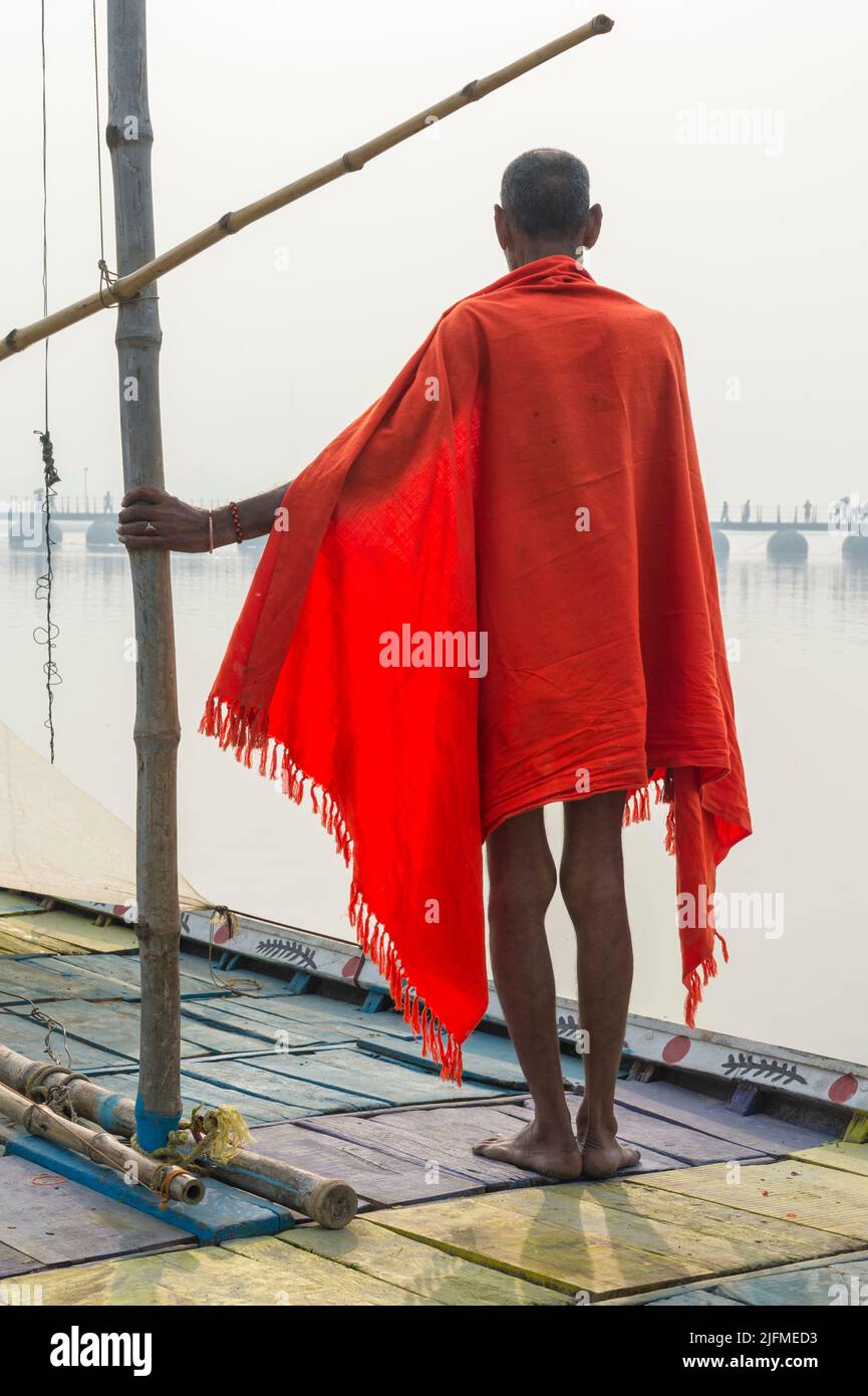 Sadhu with red shawl on a boat on the Ganges river at sunrise, Allahabad Kumbh Mela, World’s largest religious gathering, Uttar Pradesh, India Stock Photo