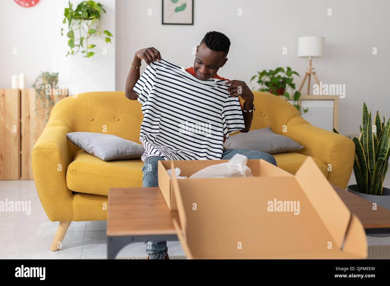 Happy african man unboxing package after delivery Stock Photo