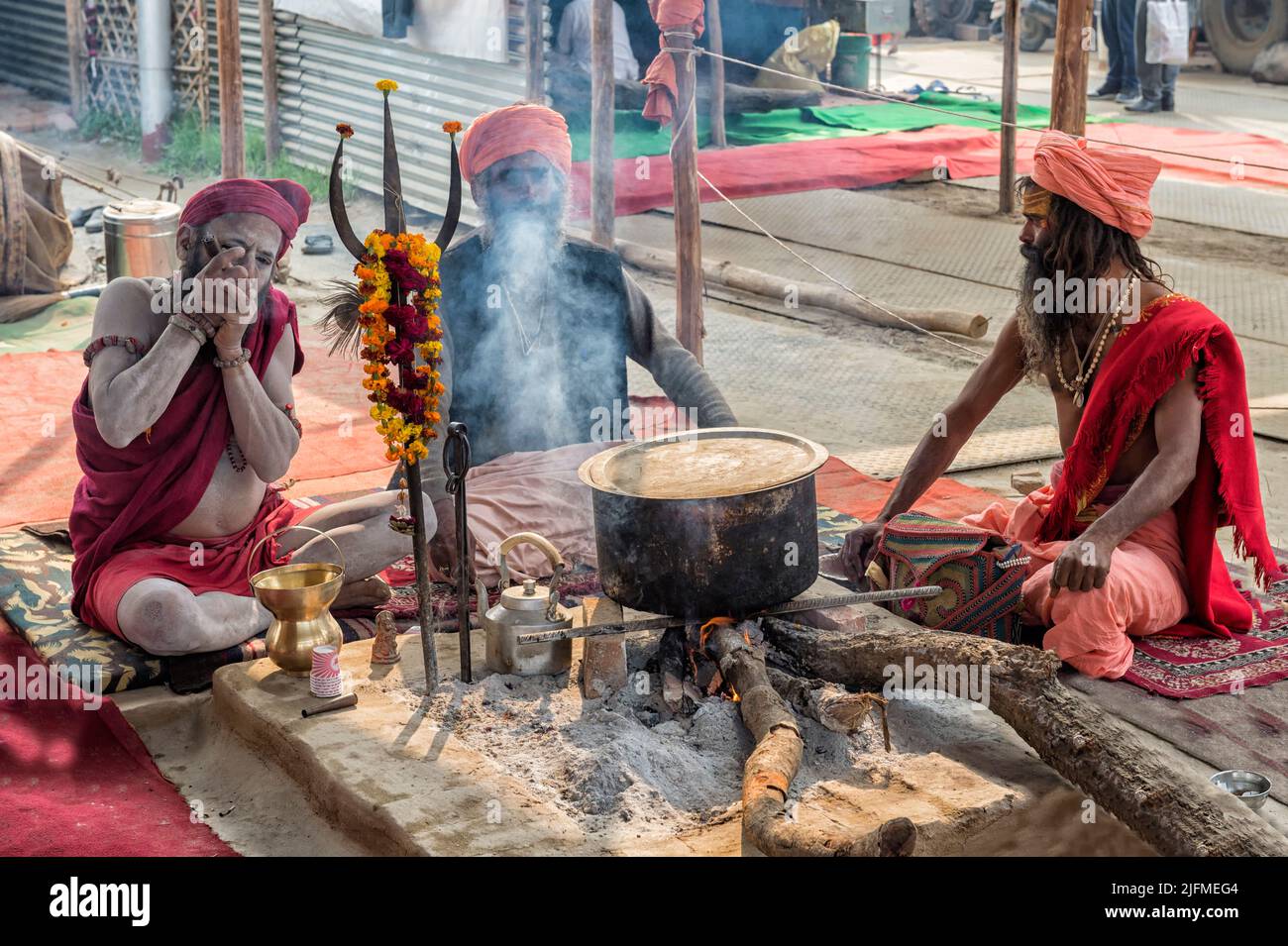 Three sadhus smoking around a fireplace, Allahabad Kumbh Mela, World’s largest religious gathering, Uttar Pradesh, India Stock Photo