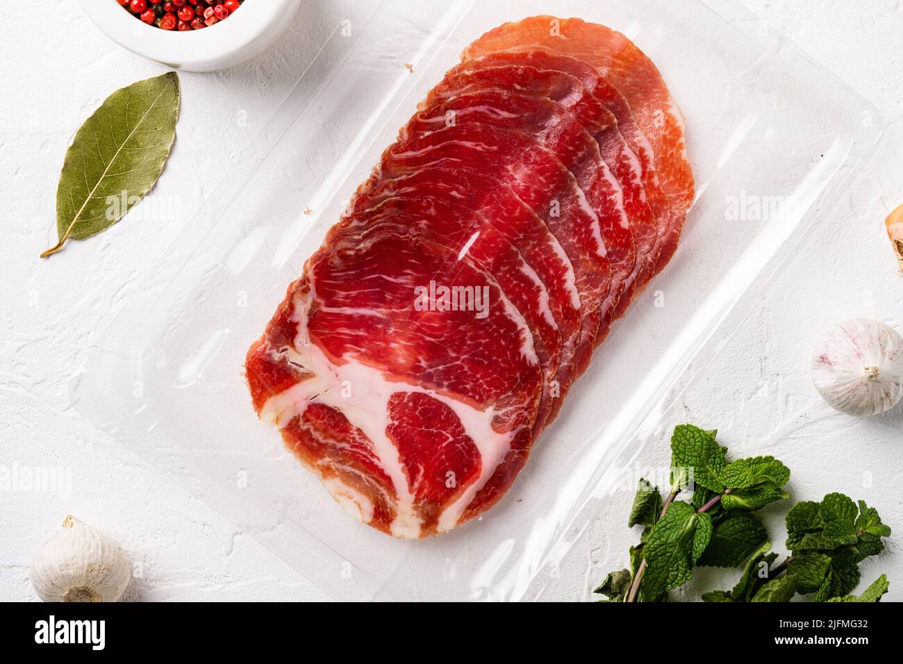 Cured meat coppa pack, on white stone table background, top view flat