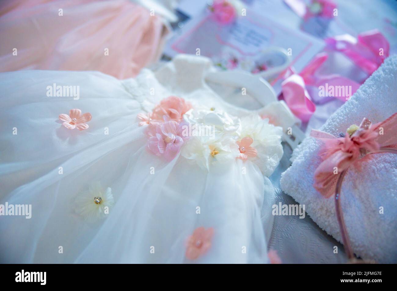 Baptism pictures. White gown baby with pink flowers outfit for religious celebration after birth. High quality photo Stock Photo