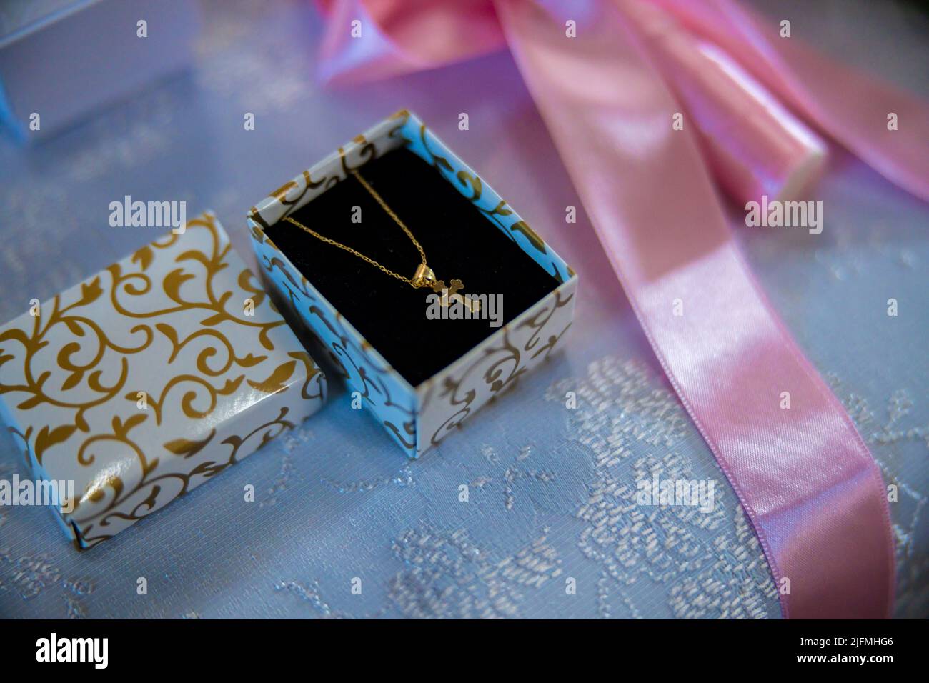 A little golden cross in a jewelry box prepared for a baby's
