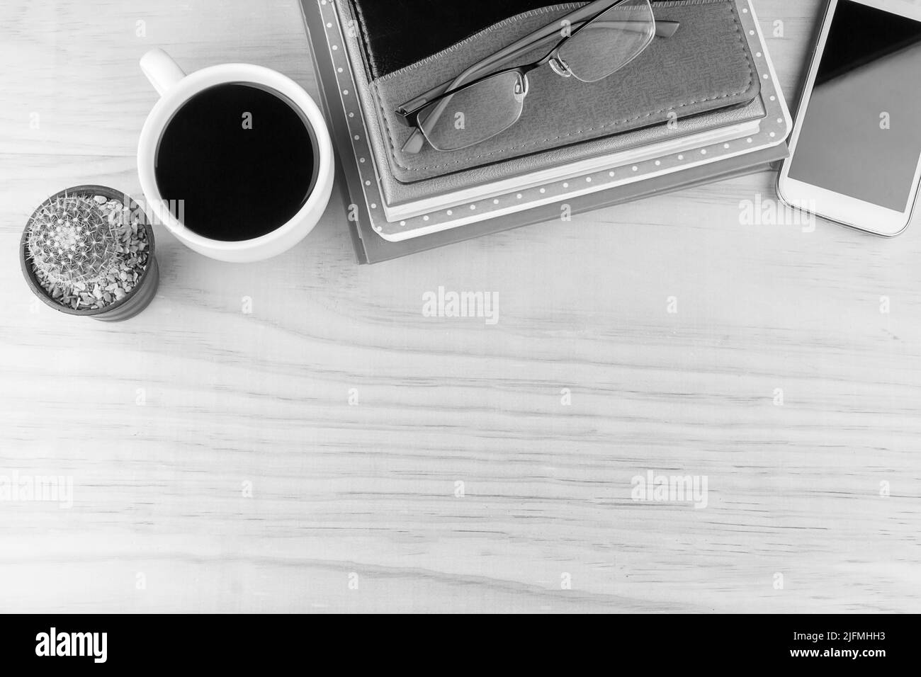 Office desk table with notebooks,glasses, smart phone and a cactus with