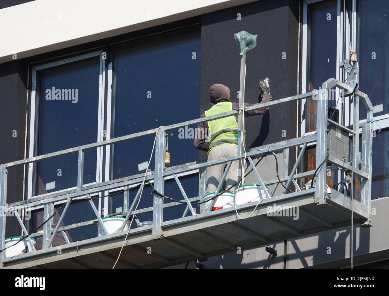 Kiev, Ukraine March 18, 2020: Workers finishing the facade of the building in suspended cradles Stock Photo