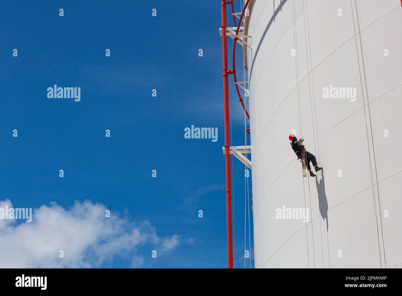 Male worker down height tank shell plate rope ladder  access safety inspection of thickness storage tank gas propane. Stock Photo