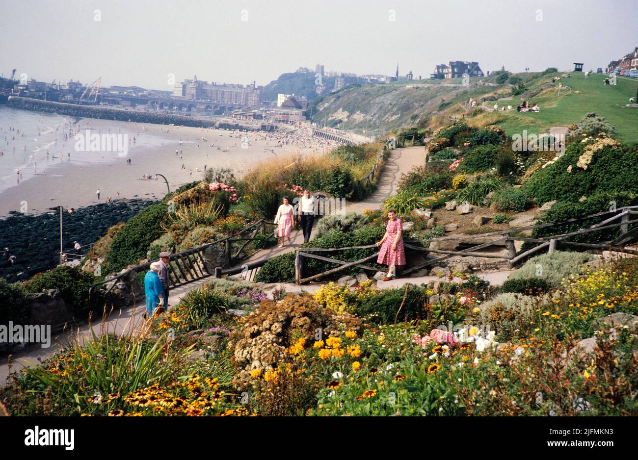 People walking through garden paths of East Cliff rockery, sandy beach
