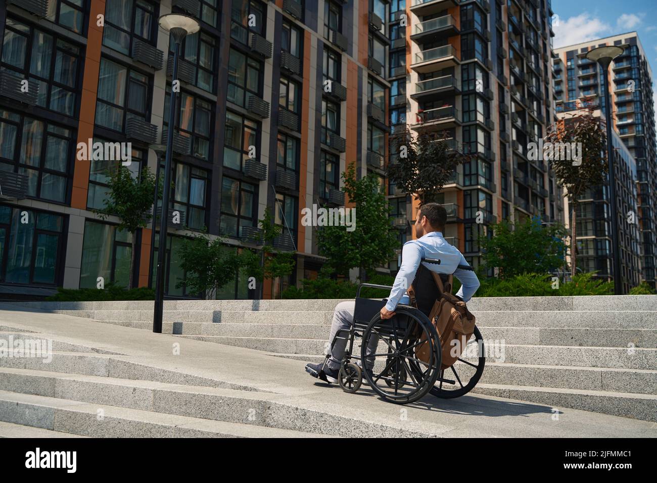 Disabled male person in wheelchair going up stairs Stock Photo