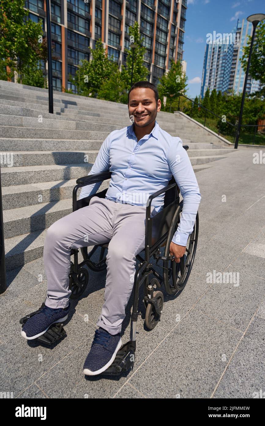Cheerful wheelchair-bound male person posing for camera outdoors Stock Photo