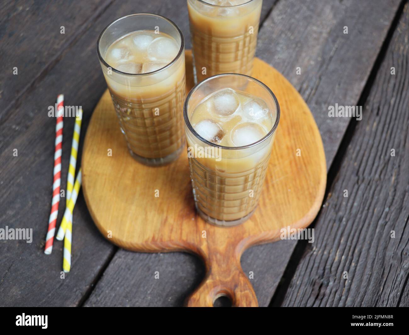 Summer drink iced coffee in tall glass on rustic wooden background. Selective focus, top view Stock Photo