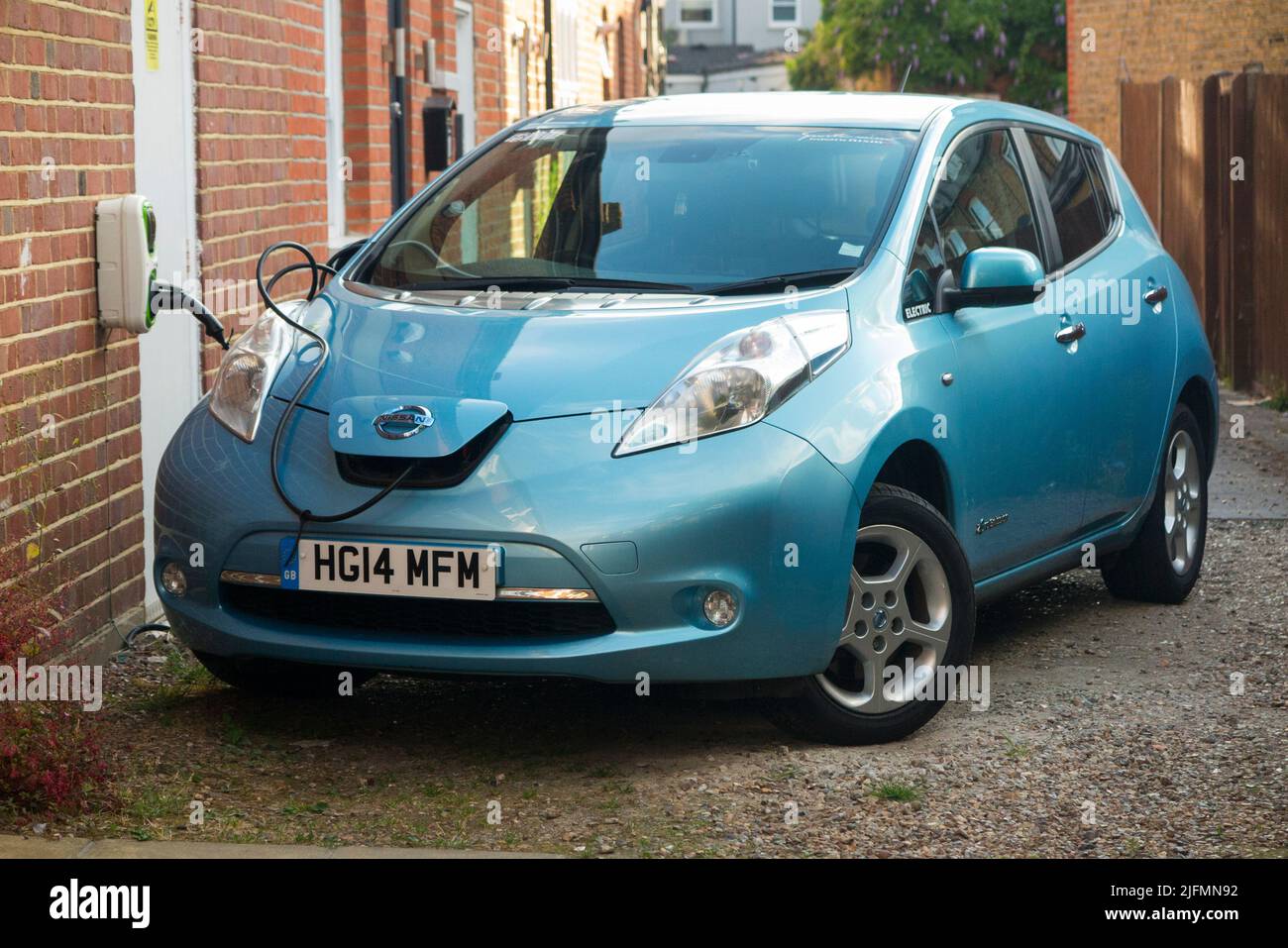 NISSAN LEAF ACENTA FLEX electric car vehicle with batteries being charged up using an electrical cable from a domestic mews house. UK. (The car numberplate has been digitally altered and it's not the real registration of this vehicle.) (131) Stock Photo