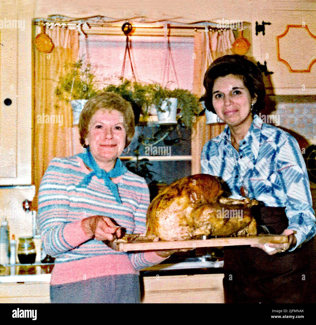 Circa 1950s, USA, two American housewives holding a large cooked turkey for Thanksgiving dinner. Stock Photo