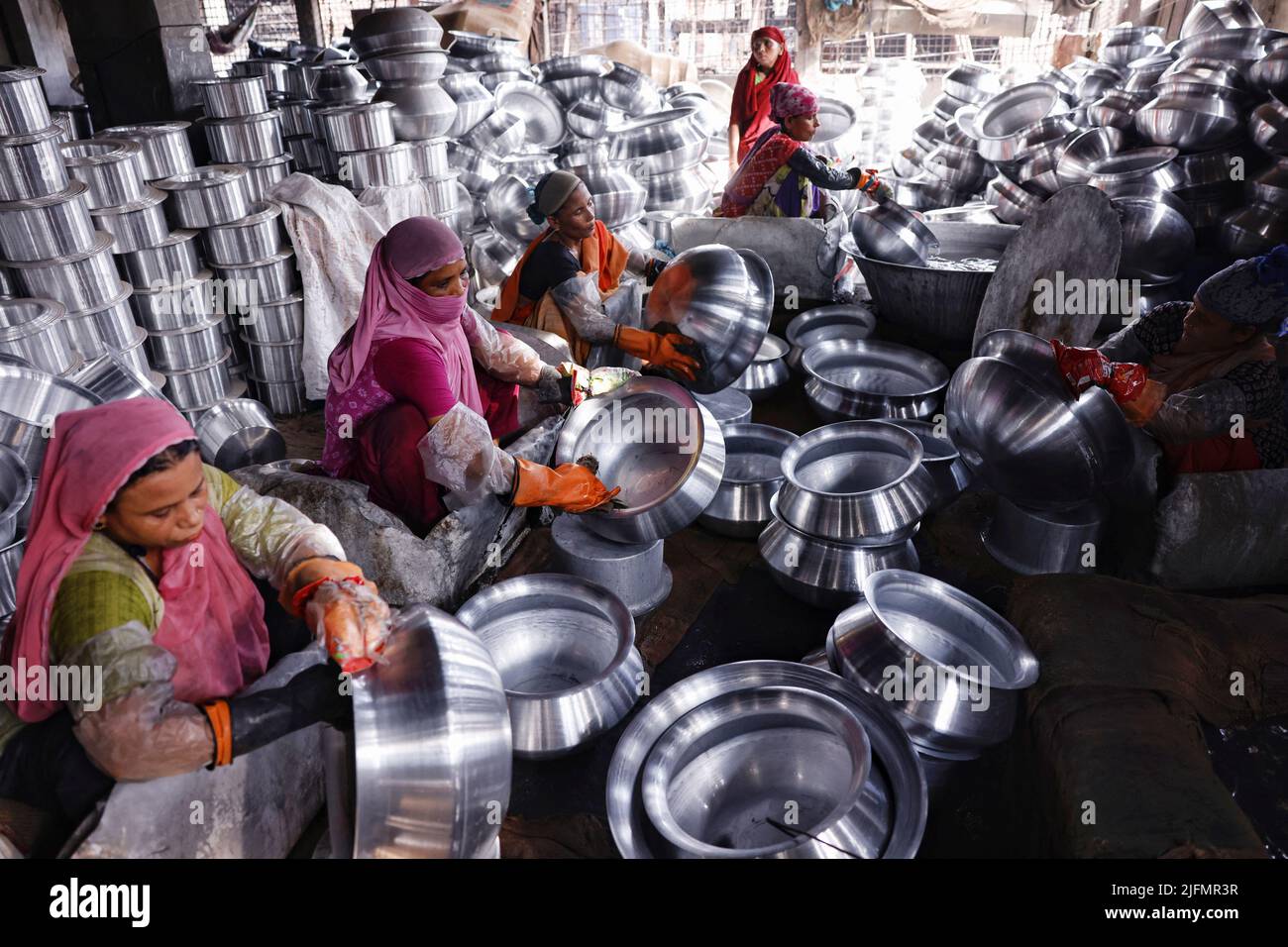 Bangladeshi women work inside a kitchen utensils factory in Dhaka, Bangladesh, July 4, 2022. REUTERS/Mohammad Ponir Hossain Stock Photo