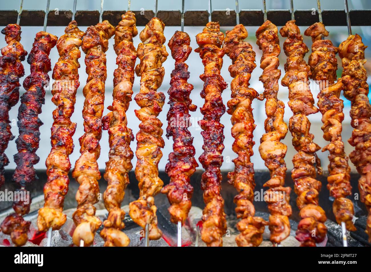 Chicken kebabs cooking on a charcoal grill at Christmas market Hyde Park Winter Wonderland in London Stock Photo