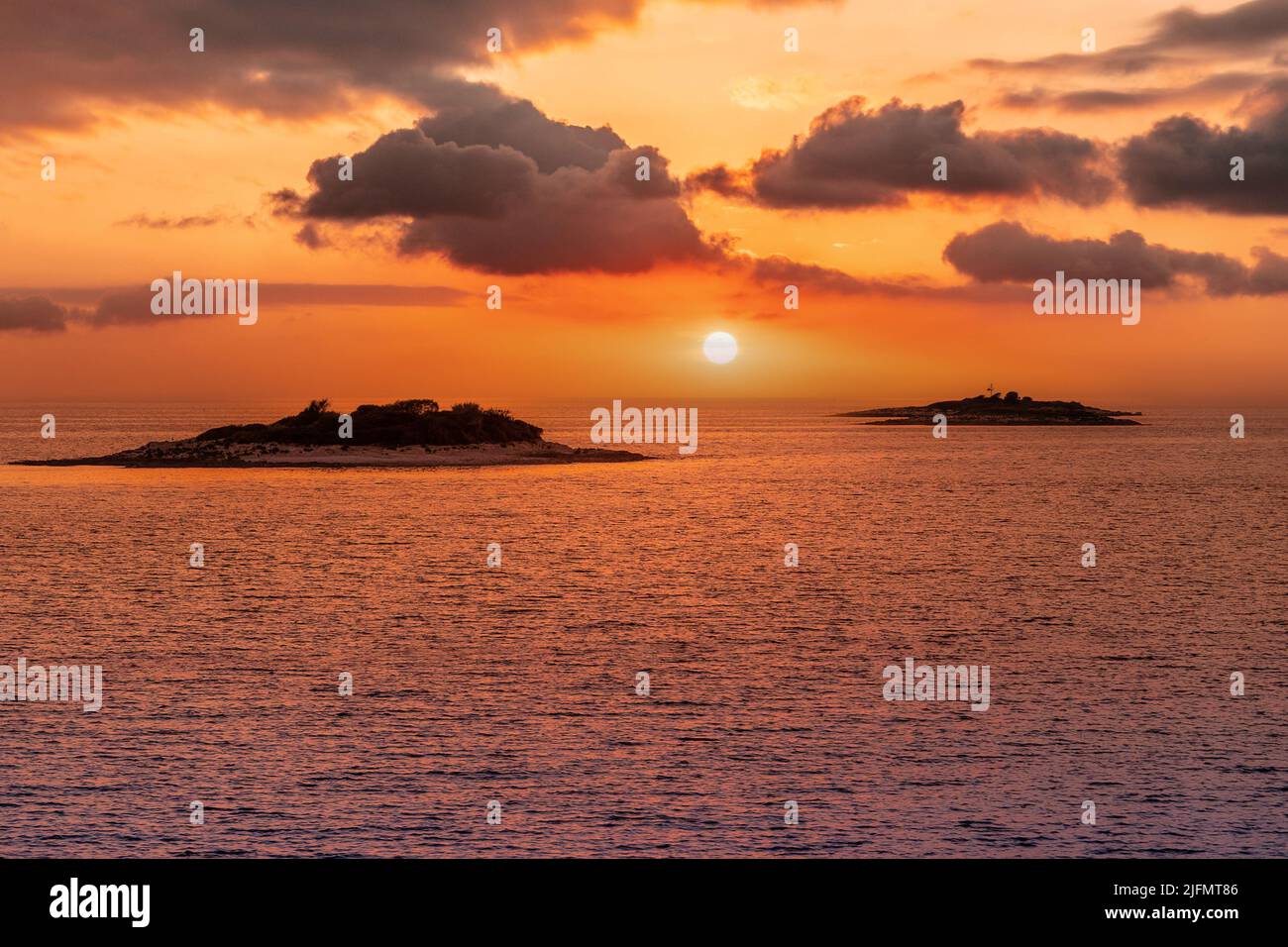 Golden Sunset into the sea with the silhouette of an island. Stock Photo