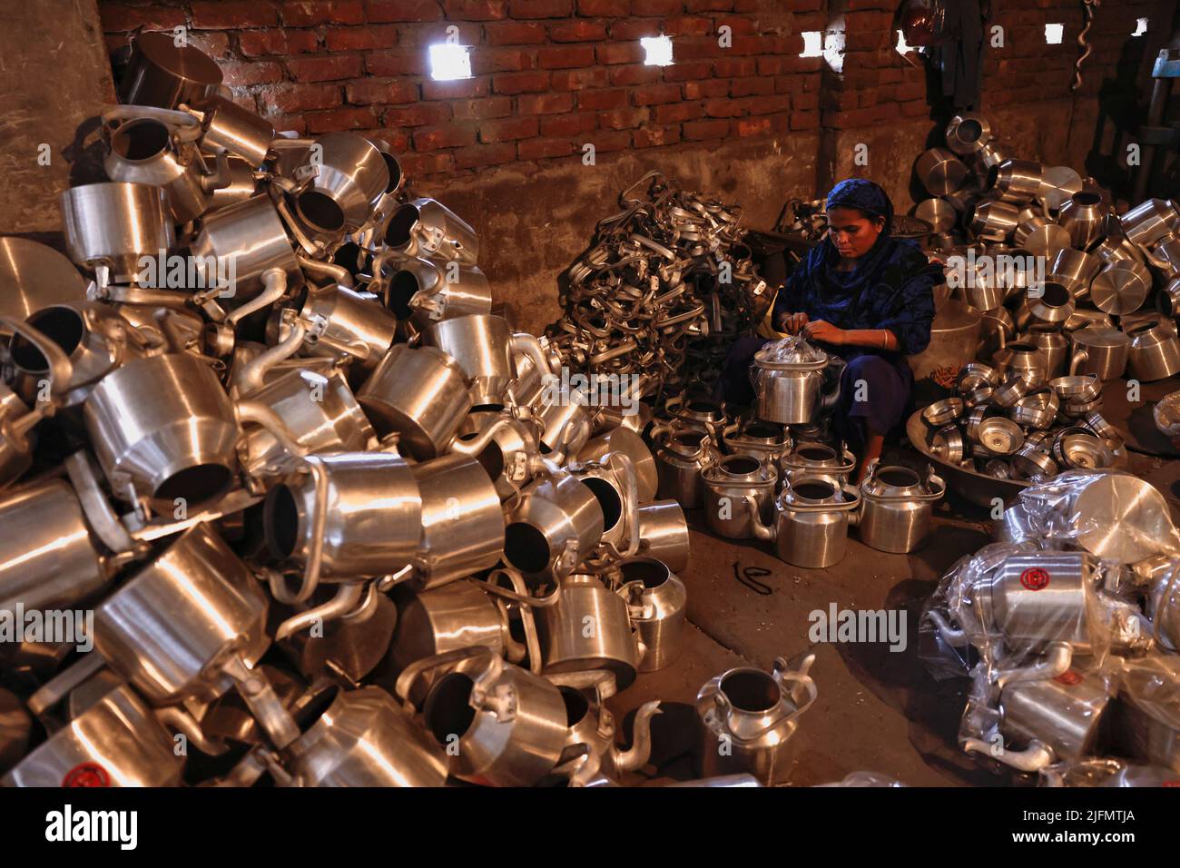 A woman works inside a kitchen utensils factory in Dhaka, Bangladesh, July 4, 2022. REUTERS/Mohammad Ponir Hossain Stock Photo