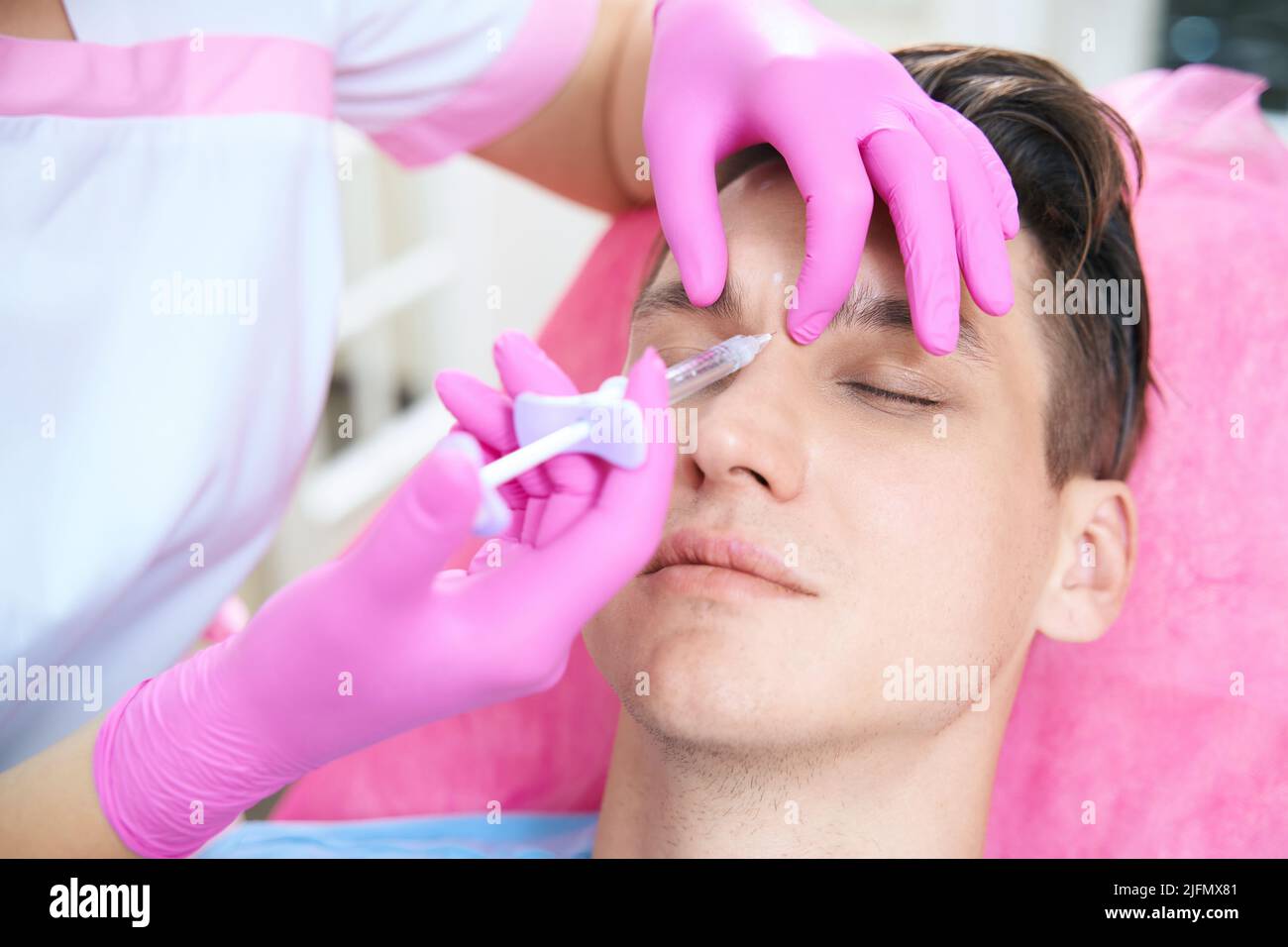 Young man receiving botox injections in beaty clinic Stock Photo