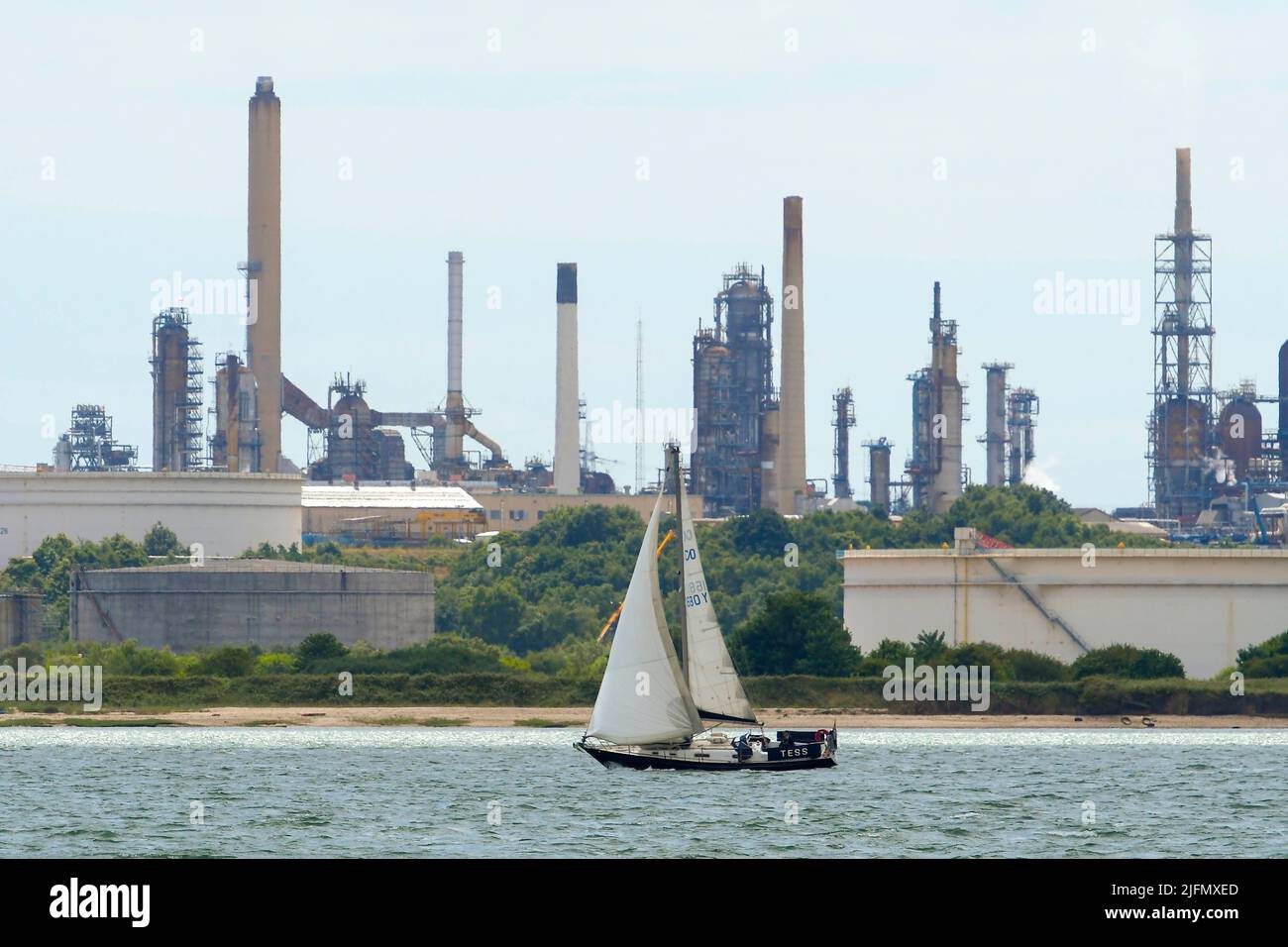 Fawley, Hampshire, UK.  4th July 2022.  General view of the Fawley Oil Refinery which sits on the banks of Southampton Water near Southampton in Hampshire which is owned by the ESSO Petroleum Company.  Pictured is a yacht sailing towards the Solent past the refinery.  Picture Credit: Graham Hunt/Alamy Live News Stock Photo