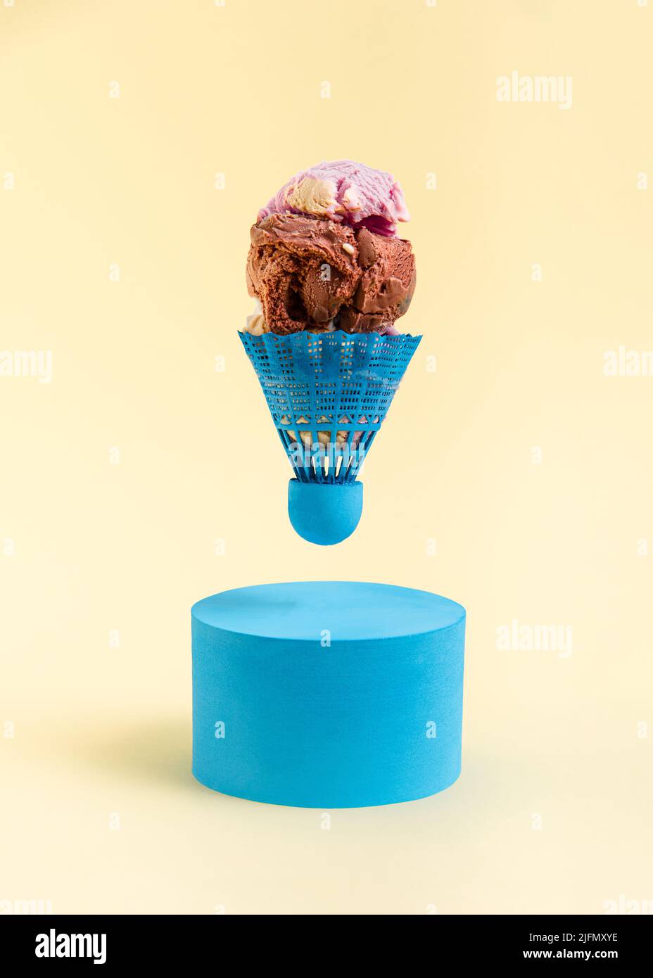 Badminton shuttlecock filled with scoops of ice cream above a blue roller on a yellow background. Minimal abstract summer concept. Rectangle layout wi Stock Photo