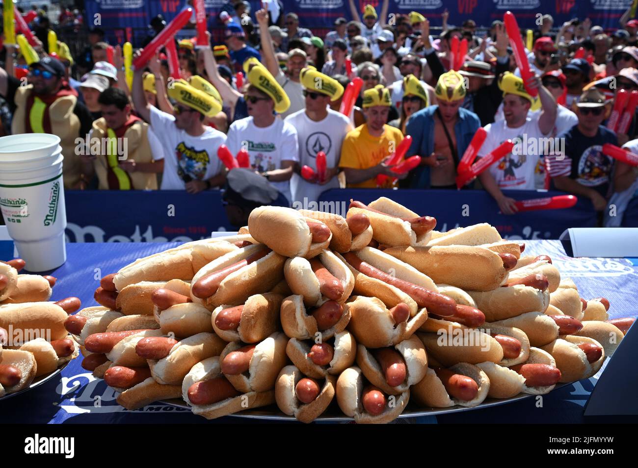 A tray of hot dogs sits before a large crowd attending Nathan's Famous