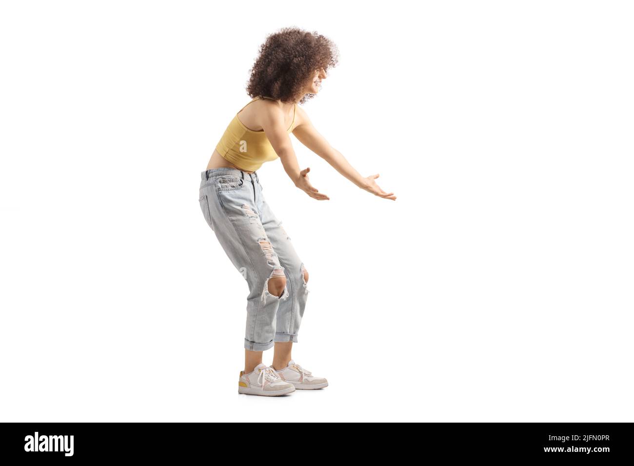 Full length profile shot of a young female with curly afro hairstyle waiting to hug someone isolated on white background Stock Photo