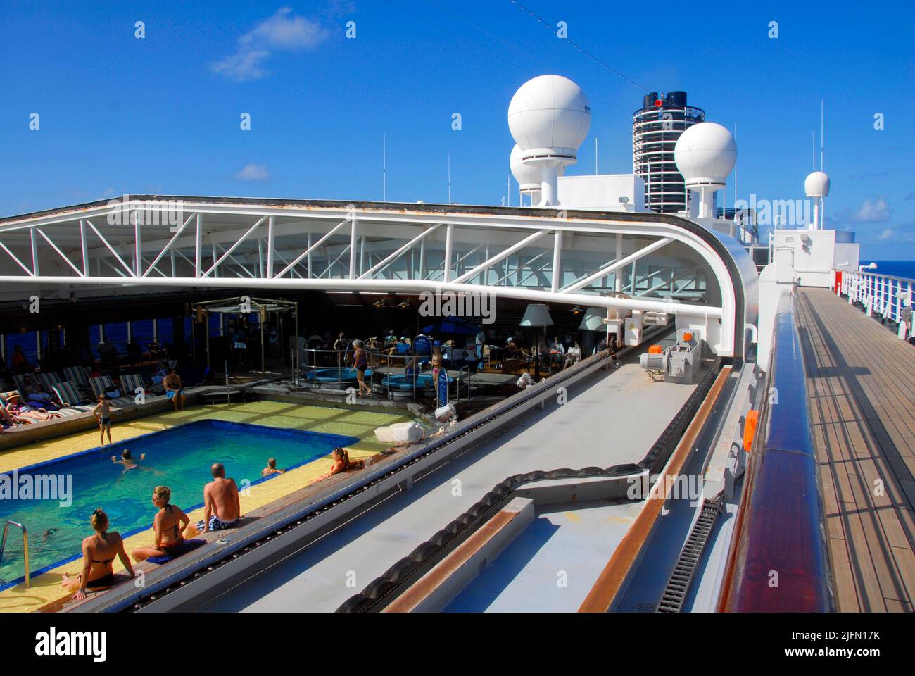 Passengers enjoying an open-air swimming pool amidships aboard a Caribbean cruise liner at sea Stock Photo