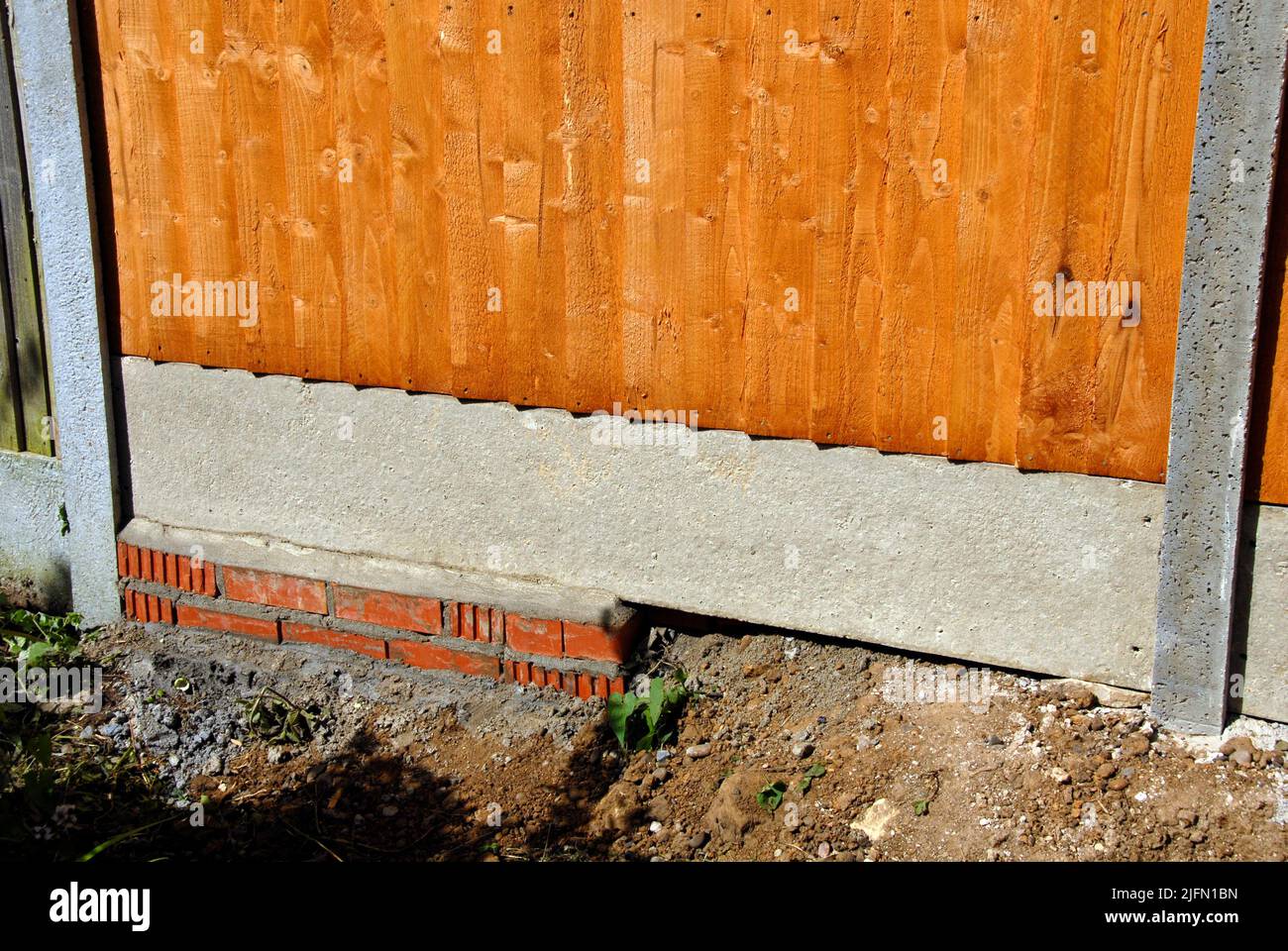 Fencing between gardens in area with undulating soil levels and poor brickwork Stock Photo