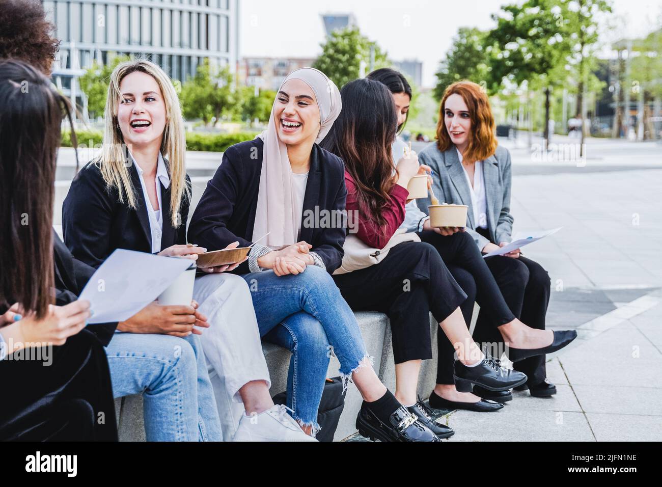 Multiethnic business women eating takeaway lunch break outdoor outside the office - Focus on arab woman face Stock Photo