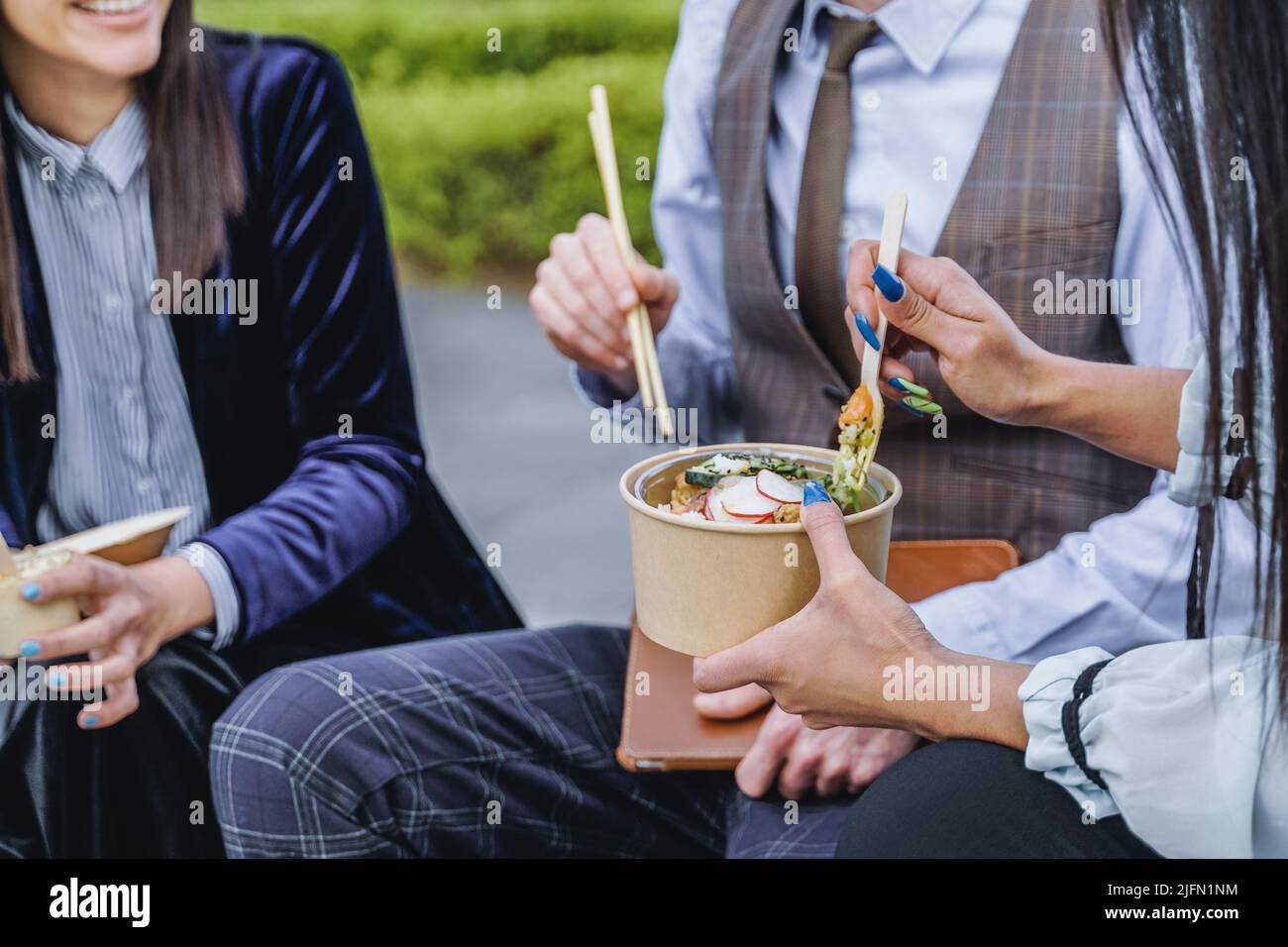 Business people eating takeaway food during lunch break outdoor outside the office - Focus on hand holding box Stock Photo