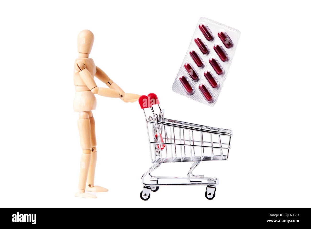 Dummy with a shopping cart dropping a blister of medicines on white background. Pharmacy and clinic concept Stock Photo