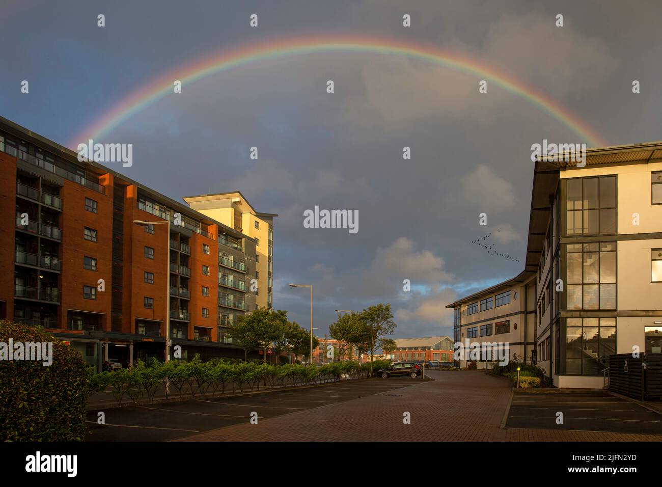 Editorial Swansea, UK - July 02, 2022: A perfect rainbow at dusk over the offices at Swansea Marina, South Wales UK Stock Photo
