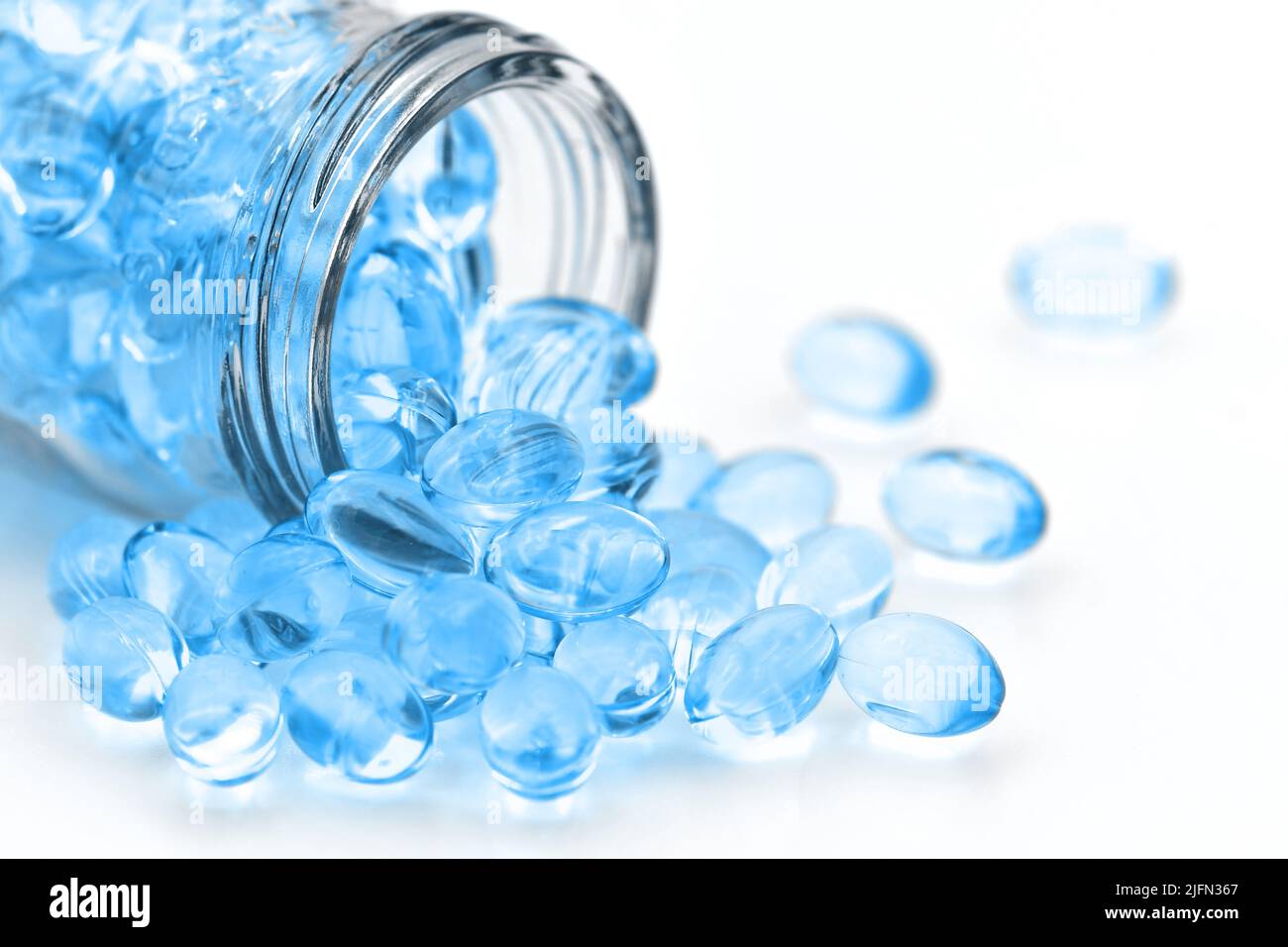 Small oval shaped of oil soft gelatin capsules in blue tone on white background. Stock Photo