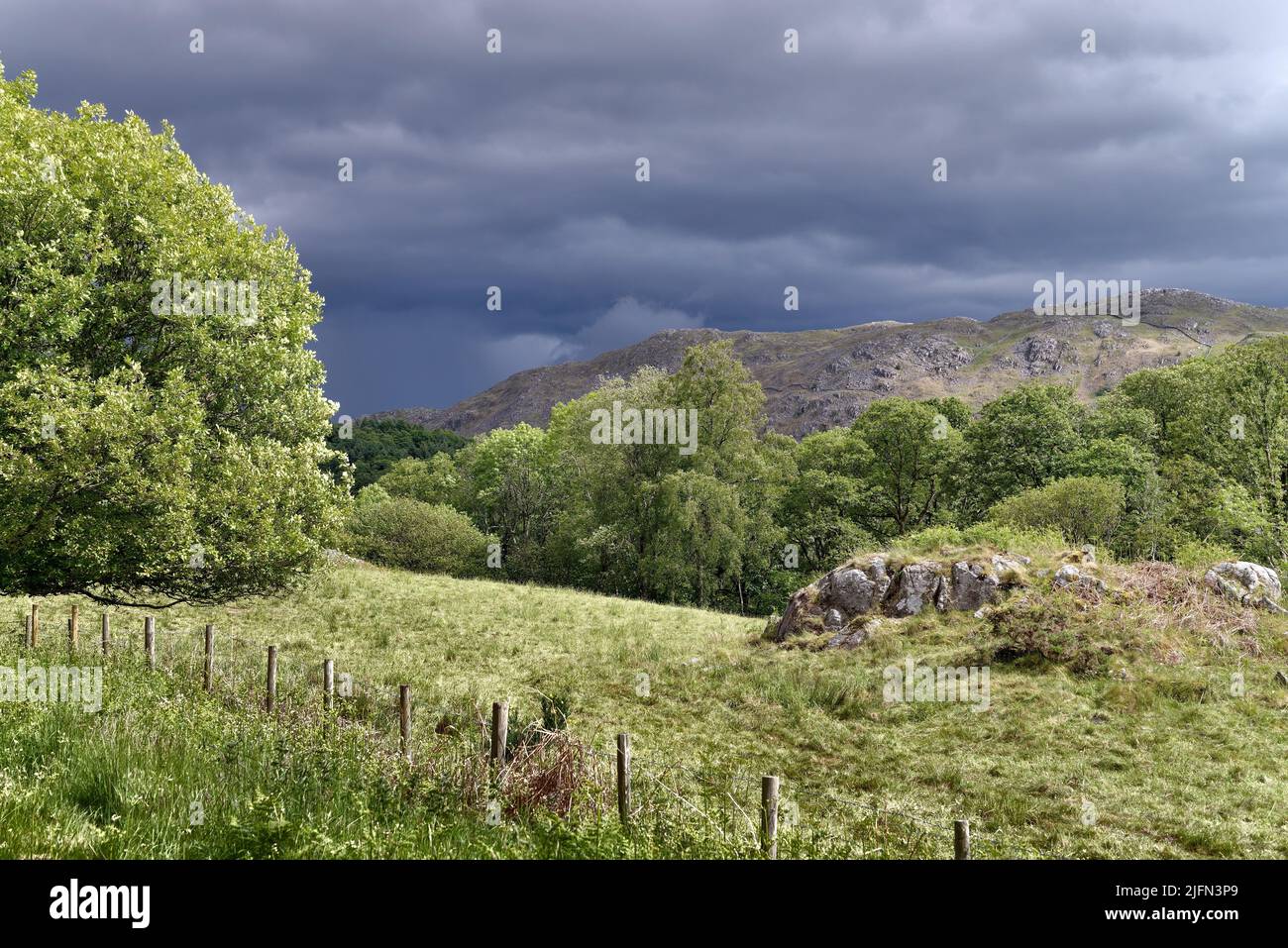 Dark storm clouds gathering over Muncaster Fell on a sunny summers day, Lake Distract  Eskdale Cumbria England UK Stock Photo