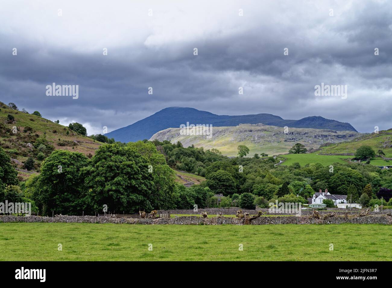 The Scafell range of mountains in storm clouds dominating the skyline in Boot  Eskdale on a summers day Lake District Cumbria England UK Stock Photo