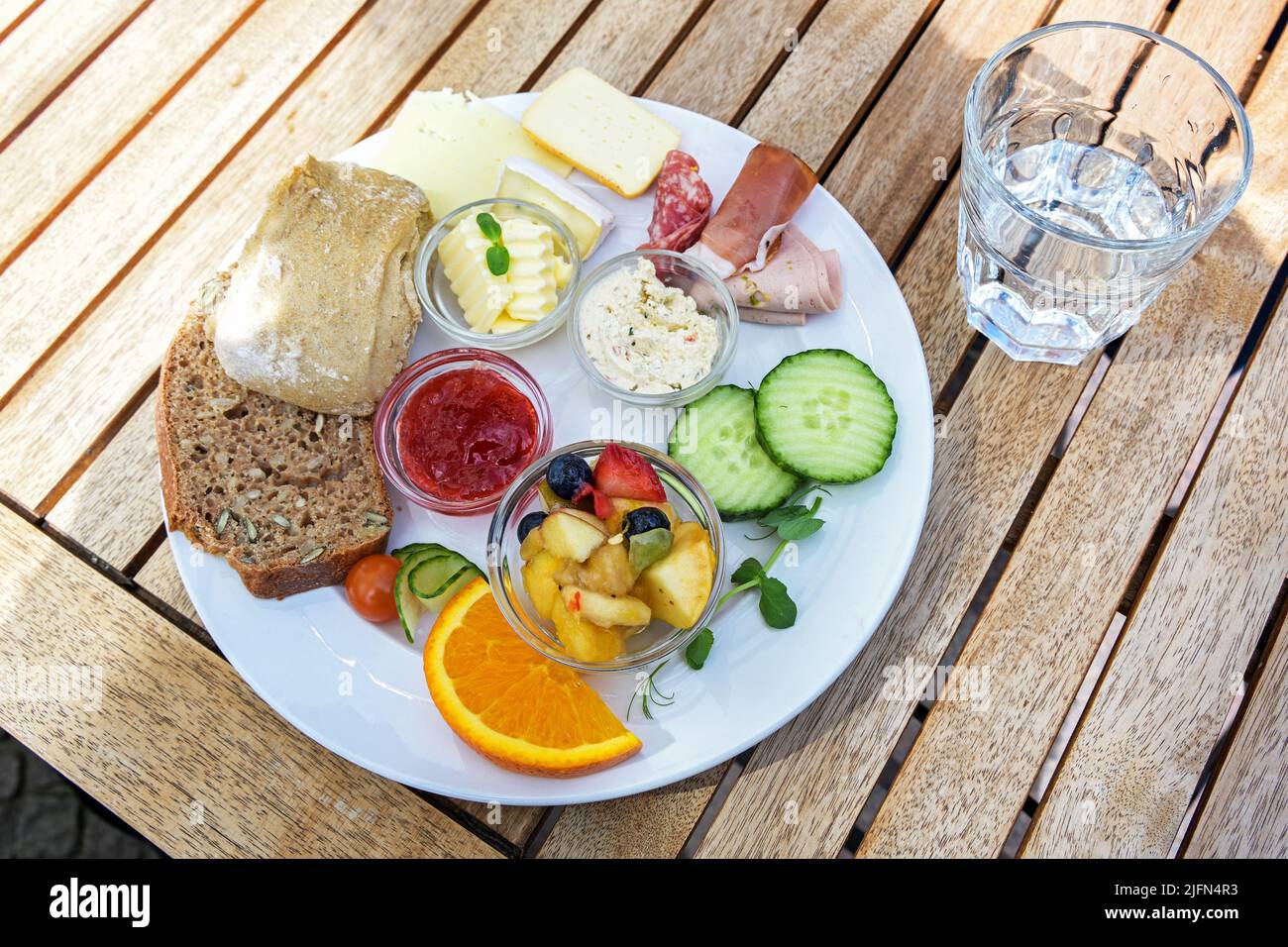 Breakfast or lunch plate with bread rolls, cheese, sausage and fruit on ...