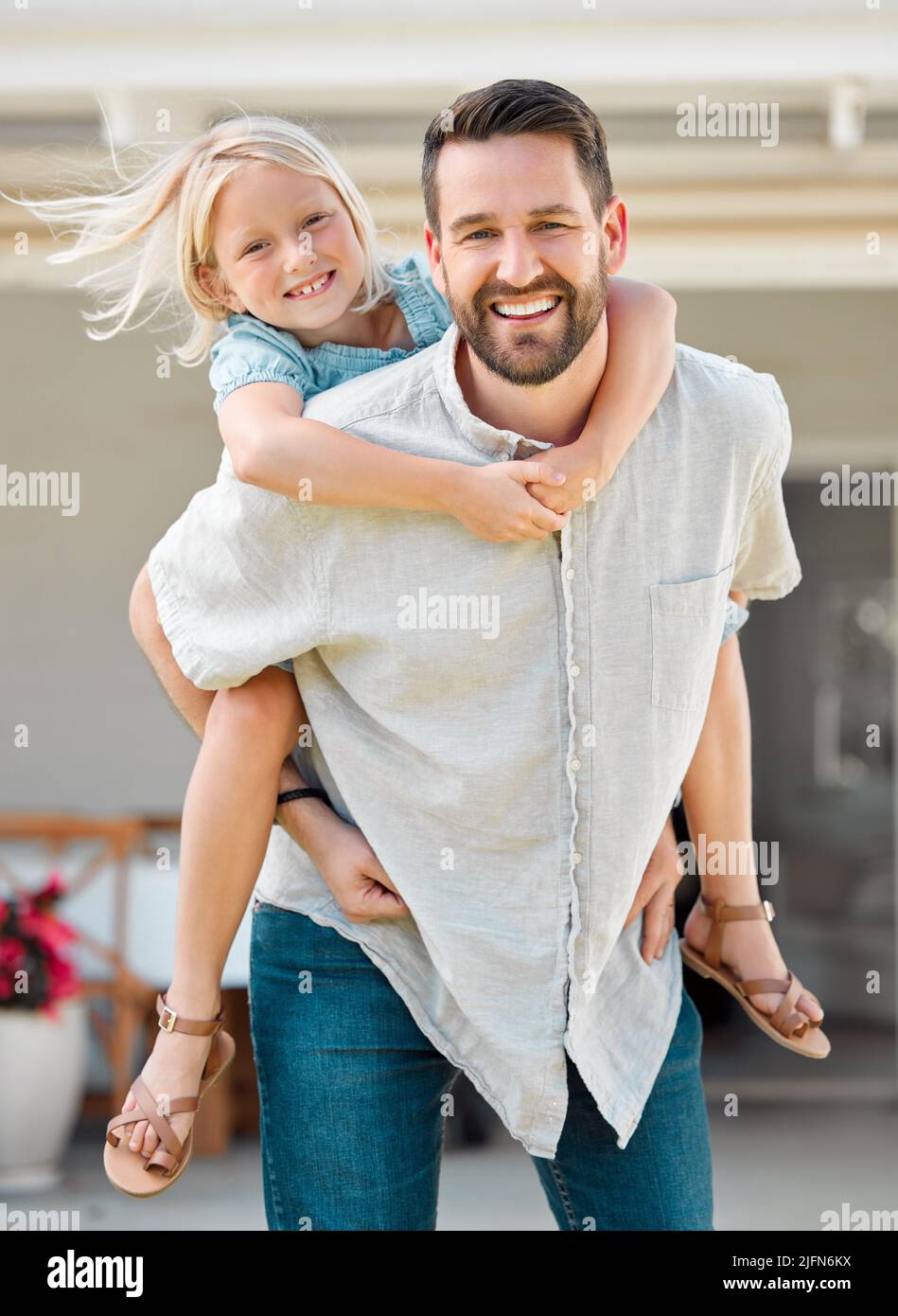 Happy single father giving his little daughter a piggyback ride outside in the garden. Smiling caucasian single parent bonding with his adorable child Stock Photo