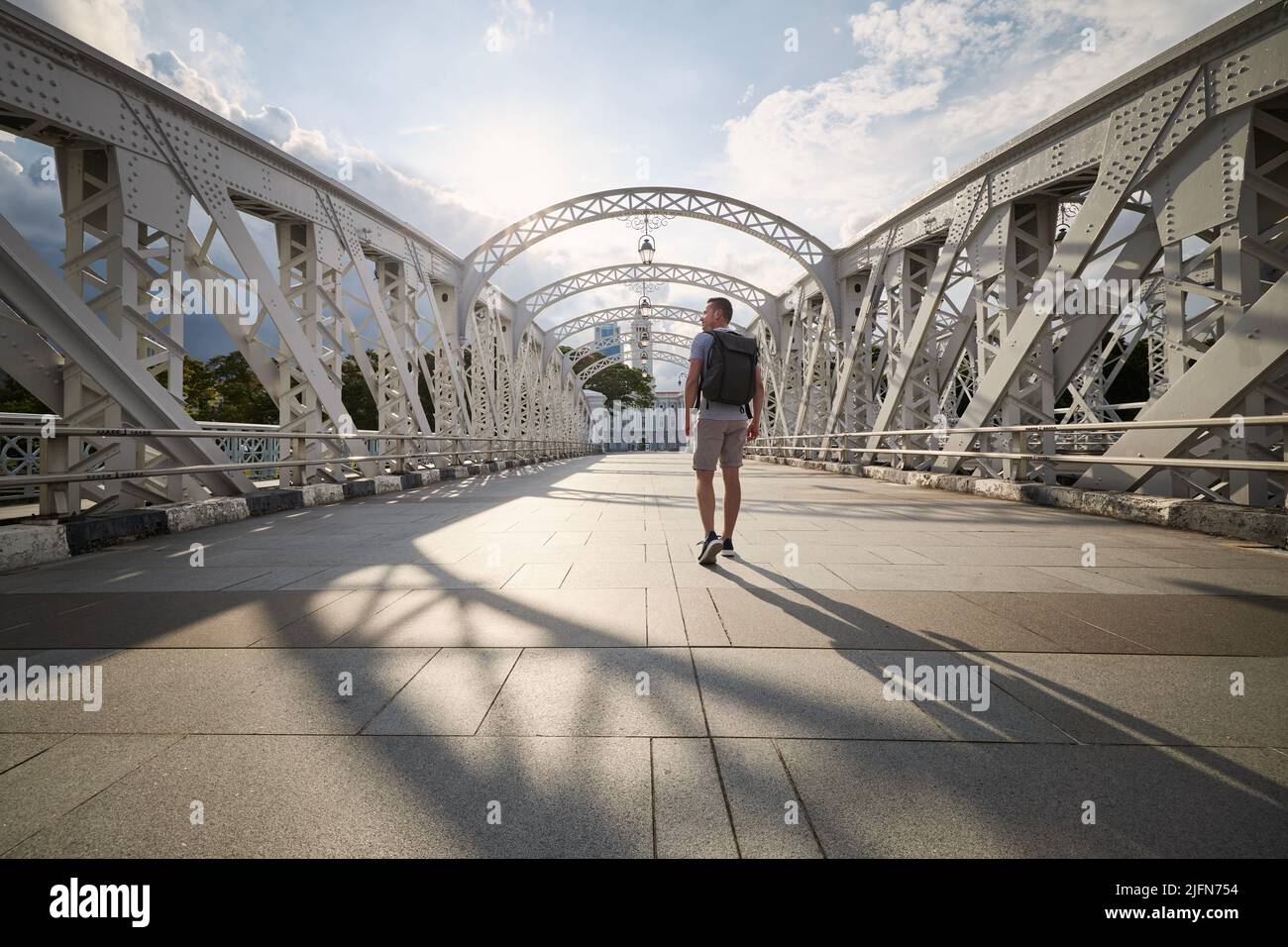 Rear view of man with backpack while walking on historical steel bridge