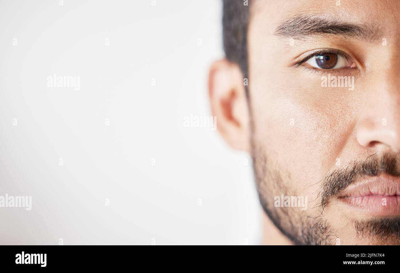 Close up of mixed race male looking serious against a grey background. Asian male standing indoors with no expression and copyspace Stock Photo