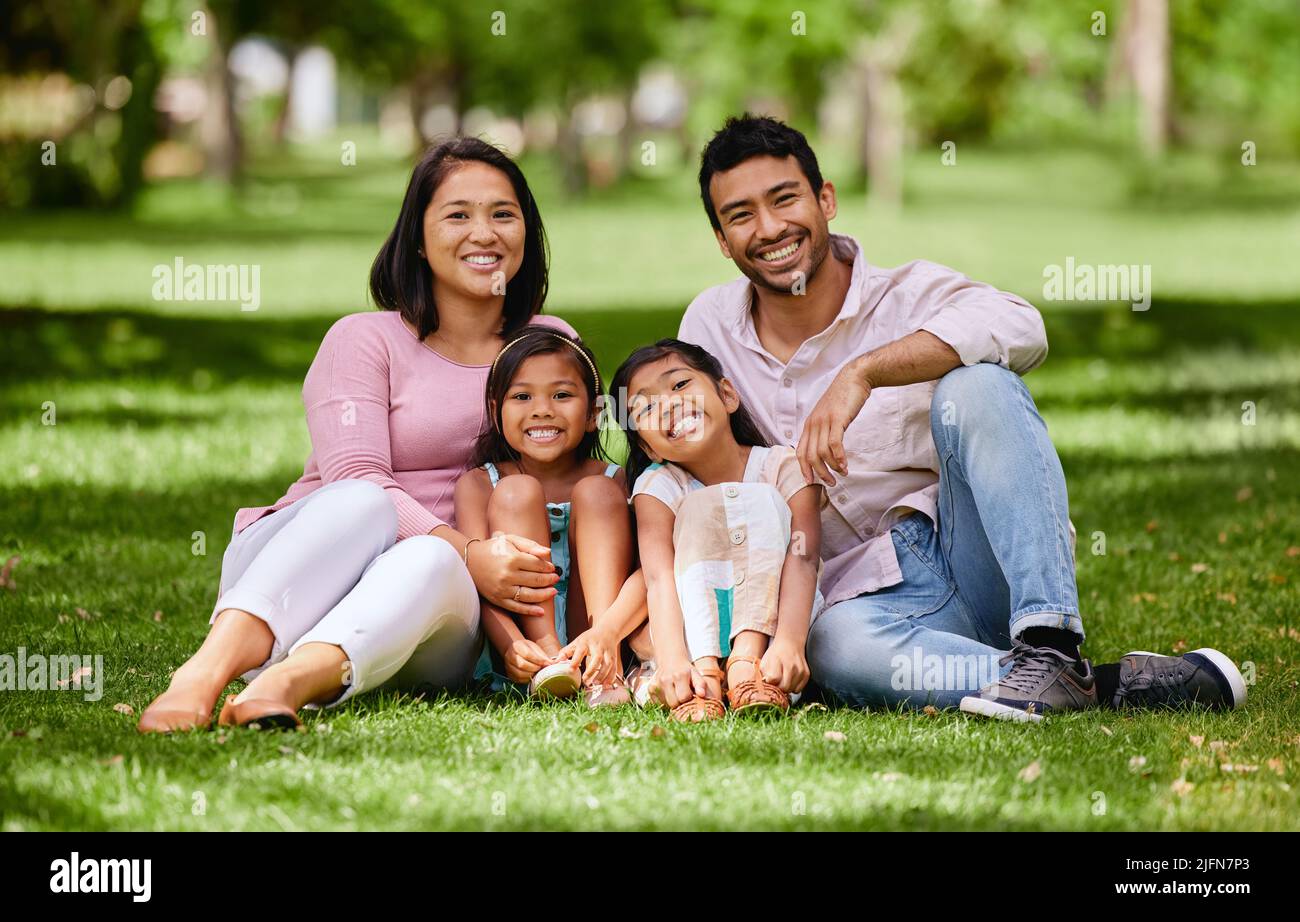 Young happy mixed race family relaxing and sitting on grass together in