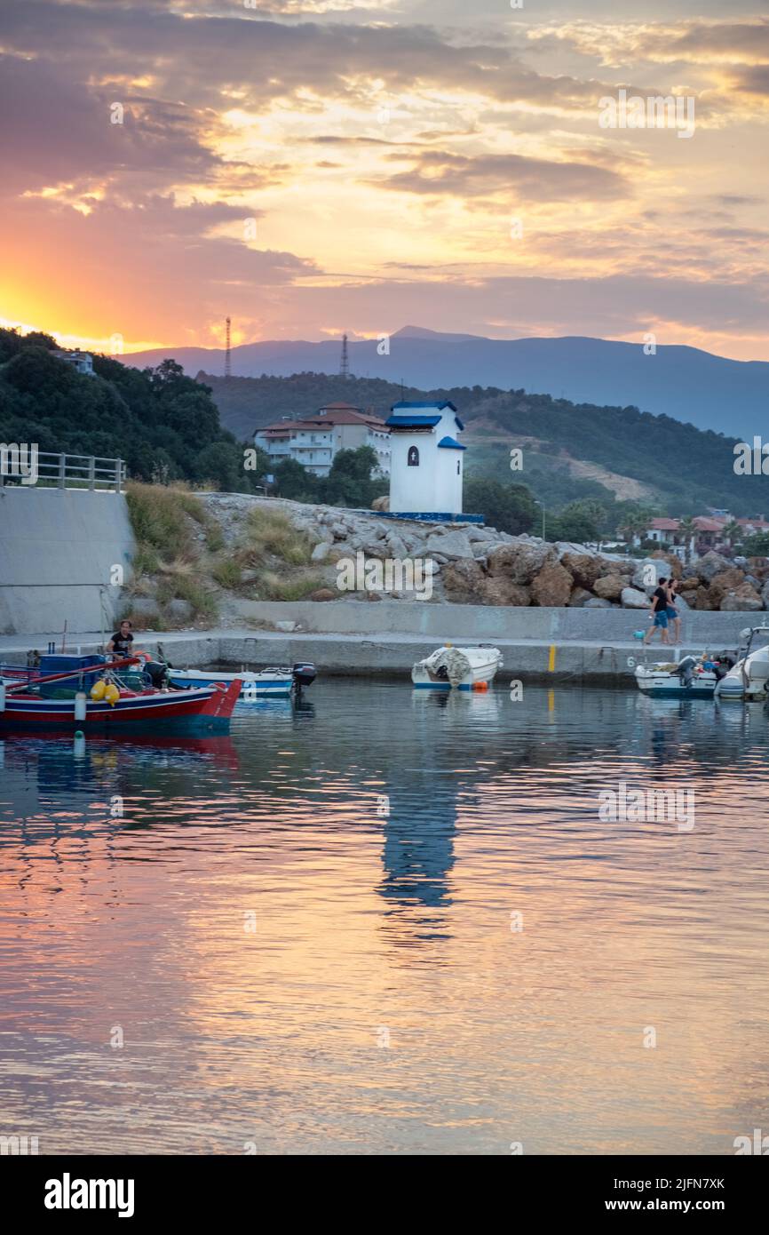 Seascape scenery of fishing boats in a harbor and a little chapel in the background Stock Photo