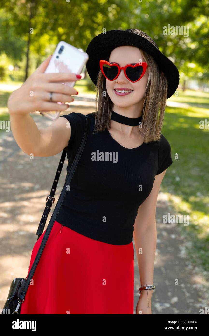 Portrait of beautiful woman makes selfie in the park Stock Photo - Alamy